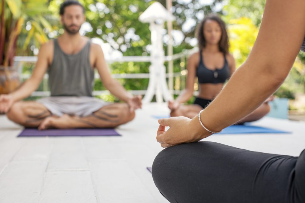 two women and a man practicing yoga on terrace