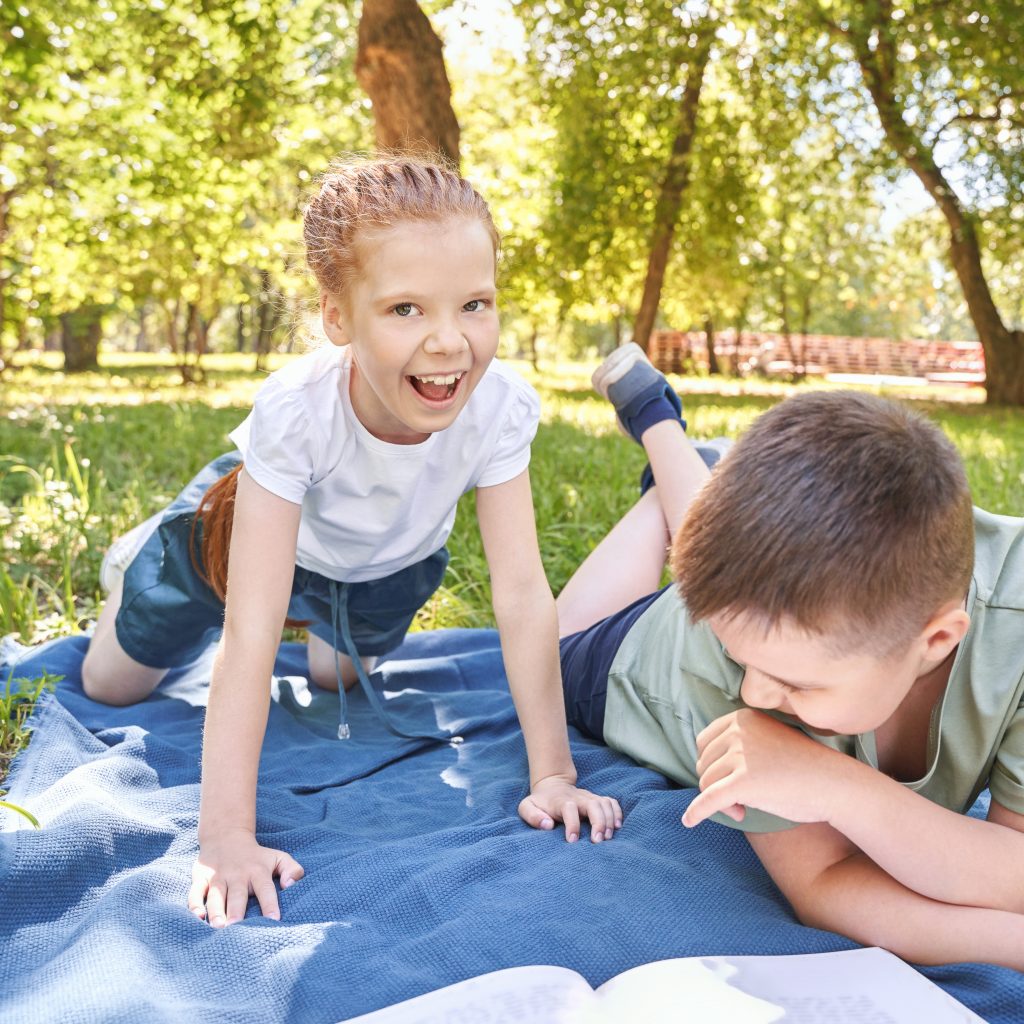 young caucasian children enjoying a relaxing day in the park on a blanket